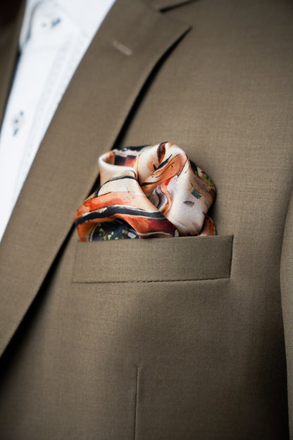 A close-up of a men's brown suit jacket with a patterned silk pocket square tucked into the breast pocket, layered over a white dress shirt.